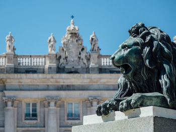 Lion statue against historic building during sunny day