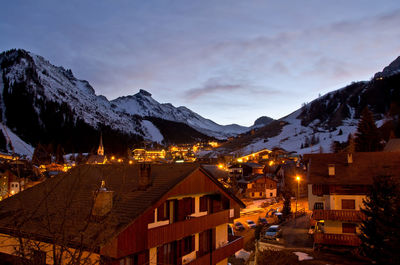 Illuminated buildings in city against sky during winter