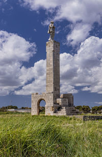 Stone structure on field against cloudy sky