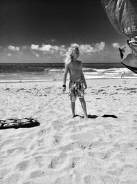 Full length of young woman standing on beach against sky