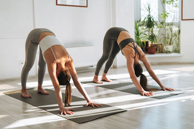 Young fit women practice yoga doing asana in a bright yoga studio