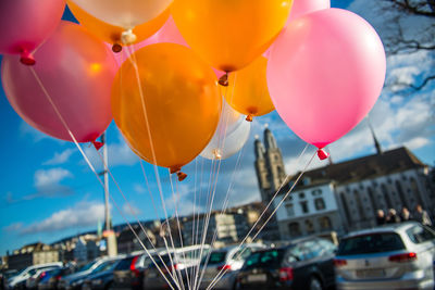 Low angle view of balloons flying in city against sky