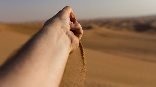 Close-up of man hand on sand