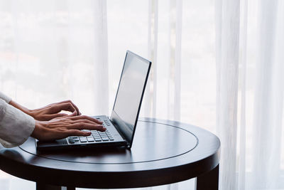 Midsection of woman using laptop at home