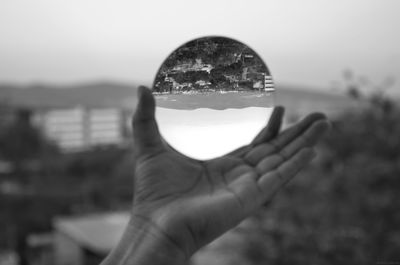 Close-up of hand holding glass against sky