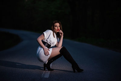 Portrait of young woman sitting on road