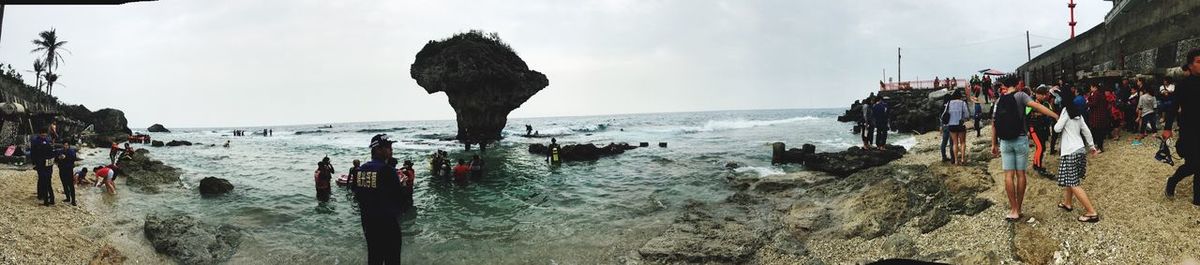 Panoramic view of people on shore against sky