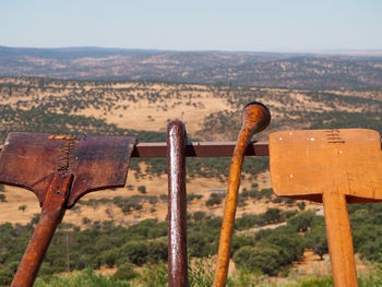 Rusty metal fence on field against sky