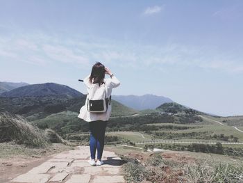 Rear view of female hiker standing against mountains