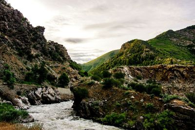 Scenic view of river by mountains against sky