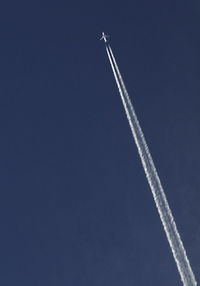 Low angle view of vapor trails in blue sky