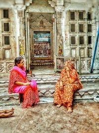 Rear view of woman sitting outside building