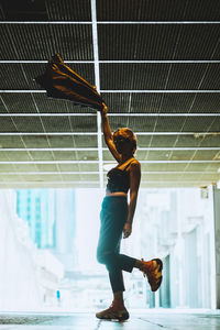 Woman spinning jacket and standing on one leg in underpass