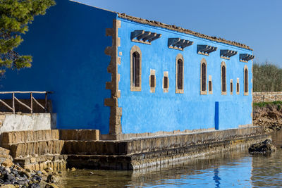 Built structure by swimming pool against blue sky