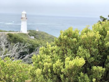 Lighthouse by sea against sky