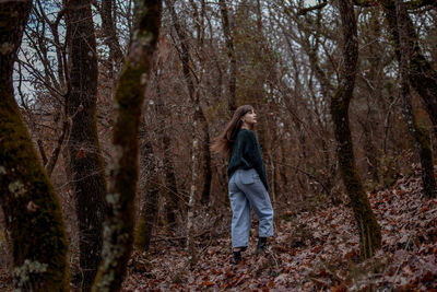 Woman standing amidst trees in forest