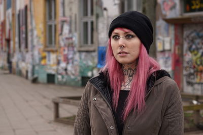 Young woman with pink hair standing on street