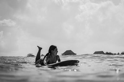 Woman sitting at beach against sky