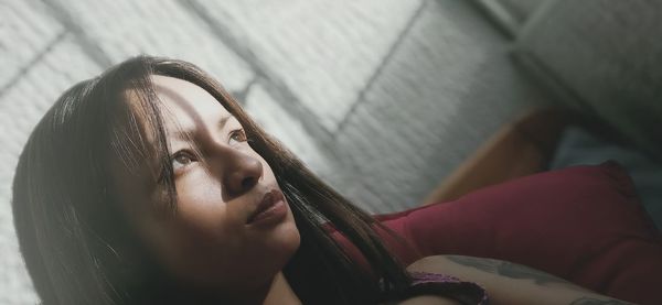 Portrait of woman lying down on bed at home