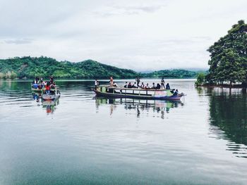 People in boat on lake against sky