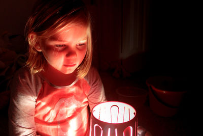 Sad girl sitting by illuminated electric light