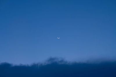 Low angle view of moon against blue sky at night