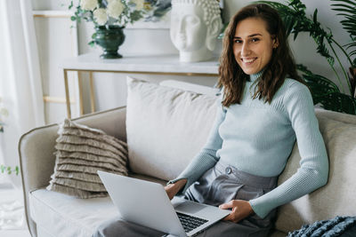 Beautiful woman on the couch working on a laptop.