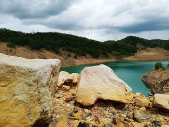 Rock formation by lake against sky