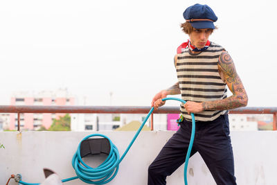 Full length of man holding railing against sky