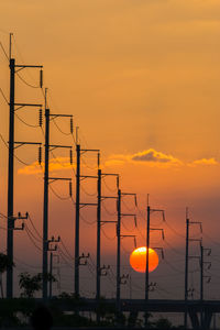 Silhouette electricity pylon against romantic sky at sunset