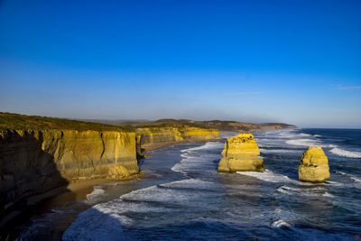 Scenic view of rocks in sea against blue sky