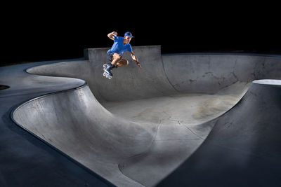 Young man practicing inline skating in skateboard park at night