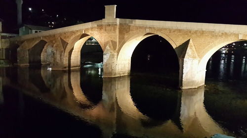 Reflection of bridge in water at night