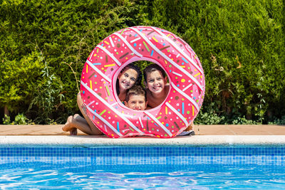 Three kids posing on a hole of a rubber ring