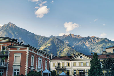 Residential buildings by mountains against sky