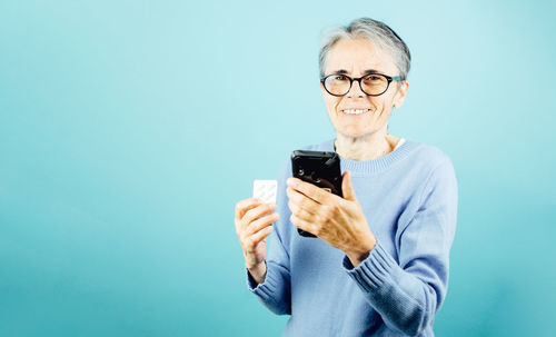 Young woman using mobile phone against blue background