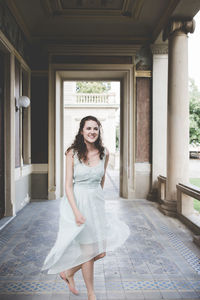 Cheerful smiling curly hair brunette in a light blue simple dress in a pavilion in a garden