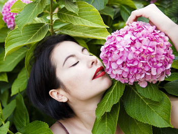 Close-up of woman with eyes closed smelling pink flowers