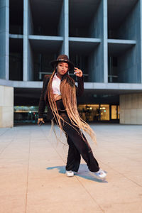 Young businesswoman dancing outside office building at dusk