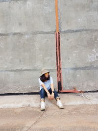 Full length of woman sitting on concrete wall