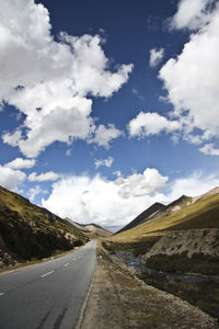 Road leading towards mountains against sky