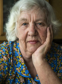 Close-up portrait of woman sitting with hand on chin at home