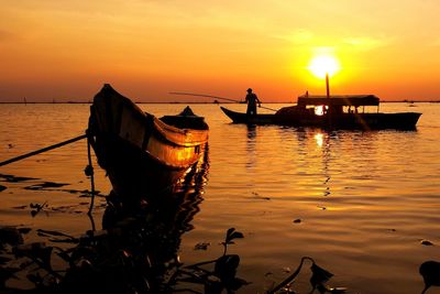 Silhouette man on boat in sea against sky during sunset