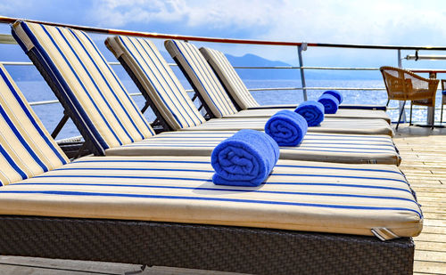 Empty chairs on table by sea against sky