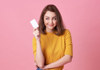 Portrait of a smiling young woman against pink background