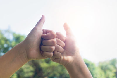 Close-up of hands against sky