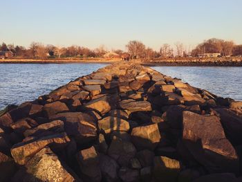 Rocks by river against clear sky