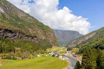 A beautiful norwegian village with a river among gorgeous lush mountains against sky