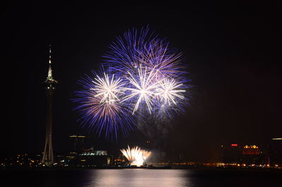 Firework display over river against sky at night