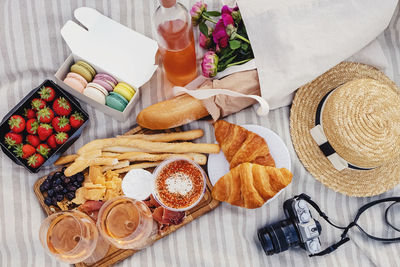 Delicious picnic with strawberries, croissants and appetizers on the board and rose wine, top view